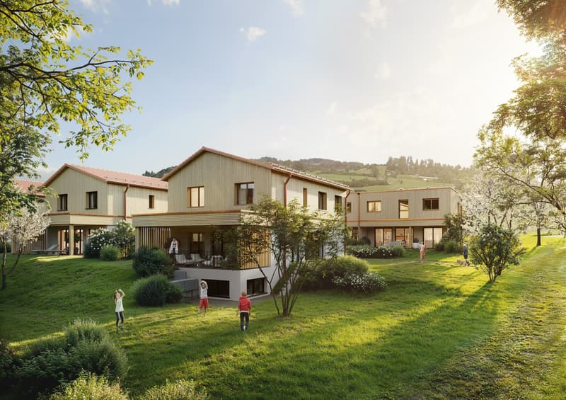 Contemporary housing project with wooden and glass facades, multiple stories, nestled in a landscaped environment with lush greenery, set on a slope with hills in the background.