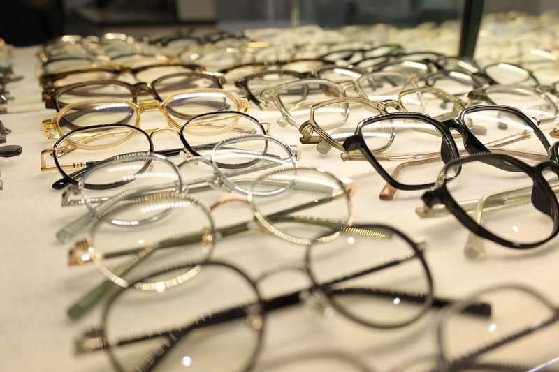 An array of eyeglasses displayed on a table in various sizes, shapes, and colors.