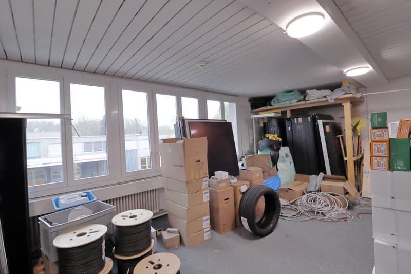 room with large windows, ceiling lights, boxes, cables, tires, shelves