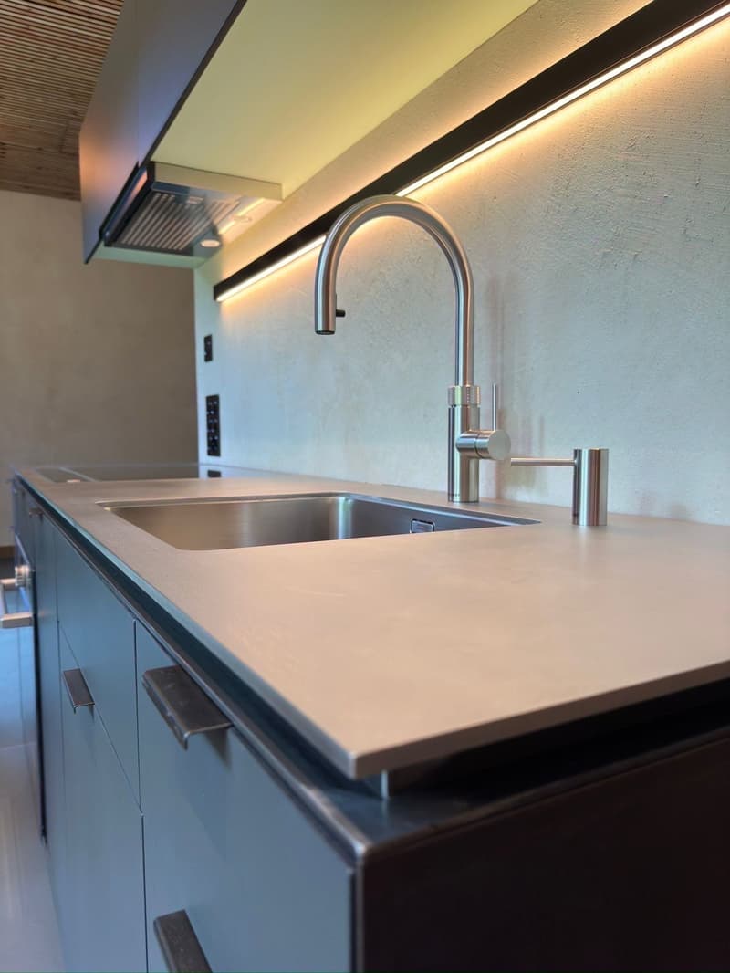 Kitchen with double stainless steel sink, gas stove, stainless steel faucet and black wooden ceiling