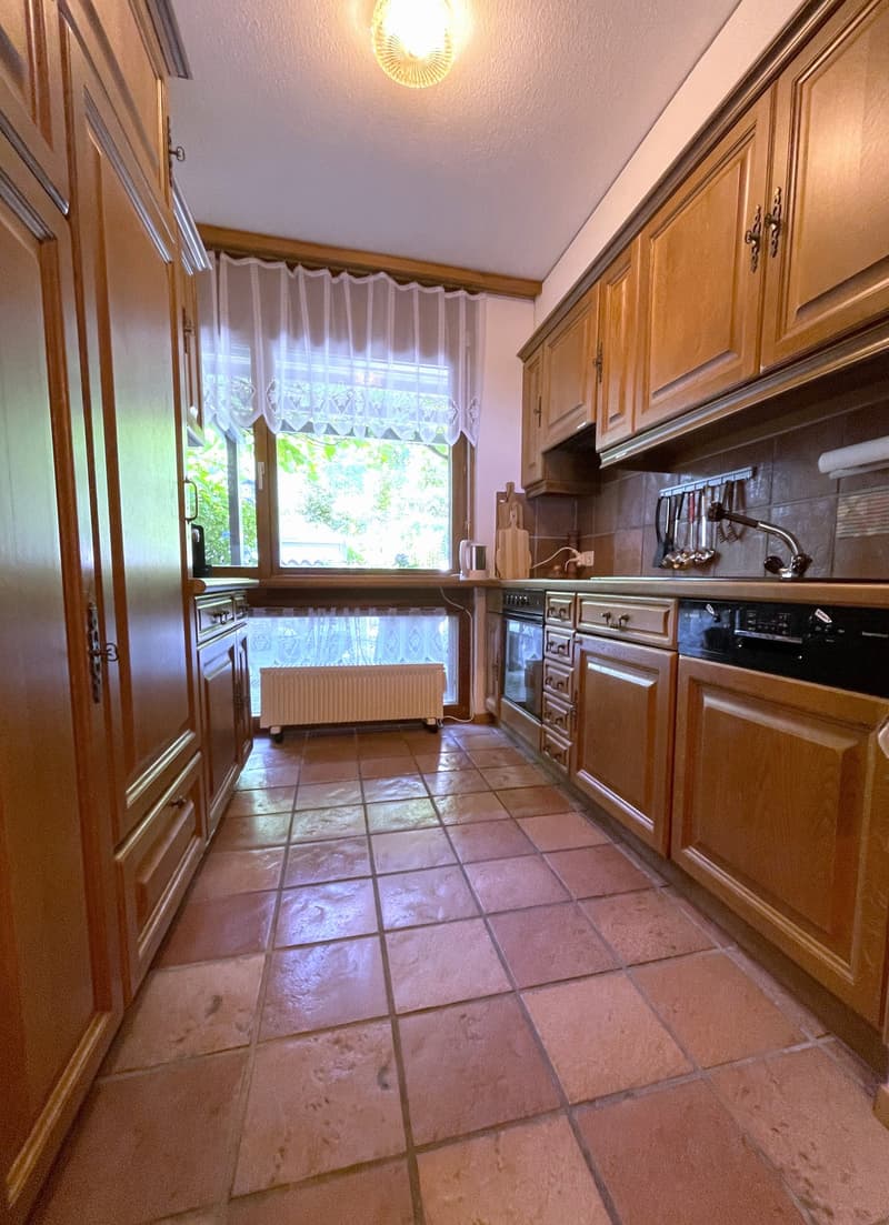 Spacious kitchen with wooden cabinets, tile flooring, and a window overlooking the outdoors. The kitchen includes a dishwasher and other appliances.