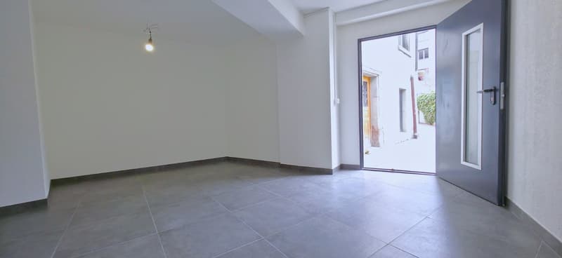 Empty room with white walls, gray tiles, open door, light fixture