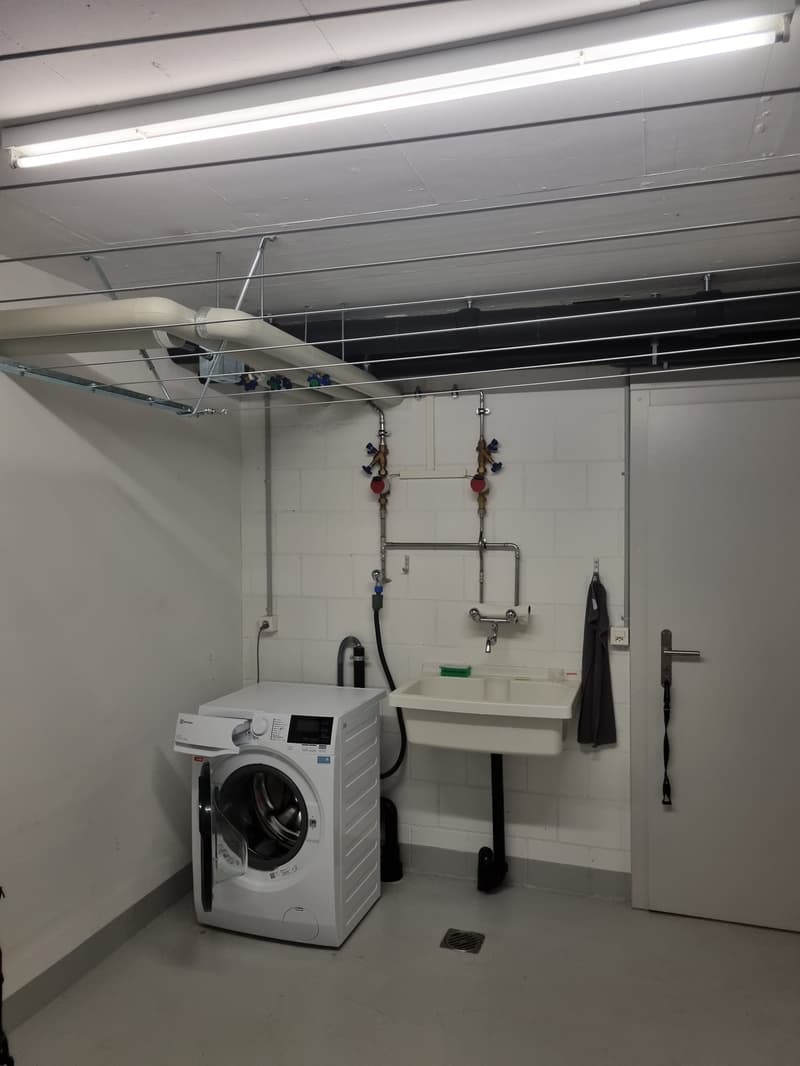 A small room with a washing machine, sink, and a towel hanging on the wall