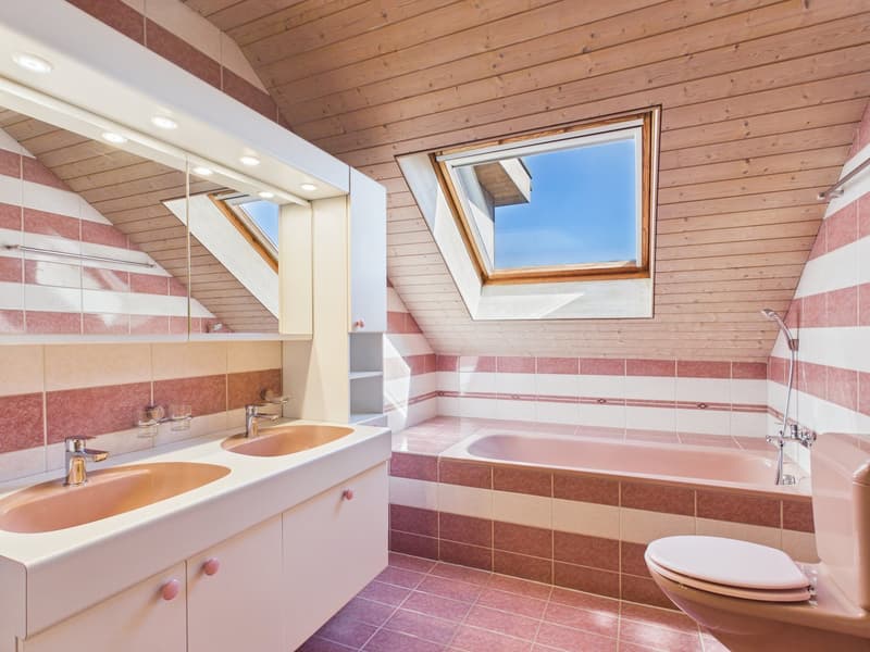 Bathroom with wooden ceiling, pink and white tiles, double sink, bathtub, toilet, skylight window