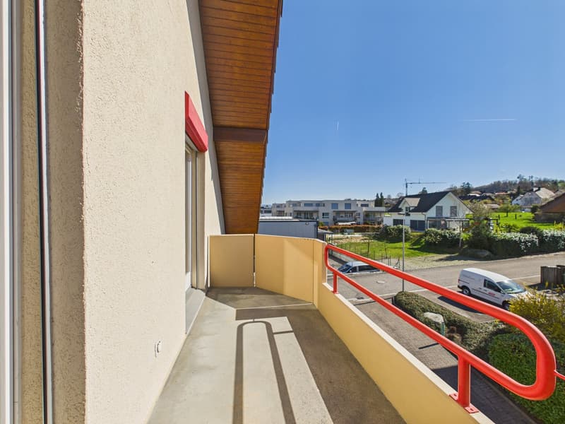 Balcony with red railings, beige walls, view of the street and houses