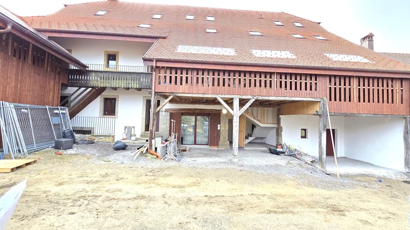 Exterior of a wooden house, red tiled roof, wooden balcony, stairs leading to the entrance, glass doors, construction site, piles of materials