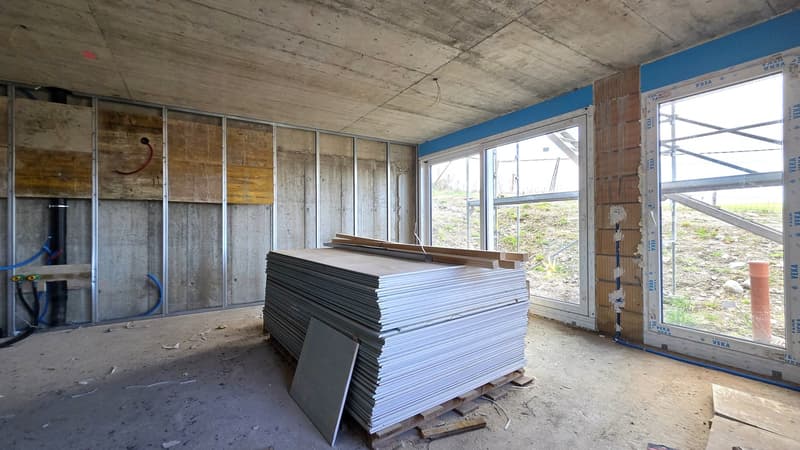 unfinished room, concrete walls, stack of building materials, large windows