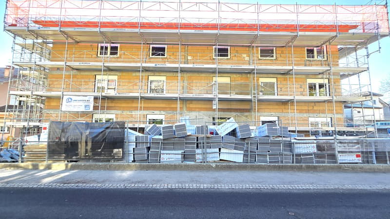 Building under construction, scaffolding, multiple windows, materials stacked in front