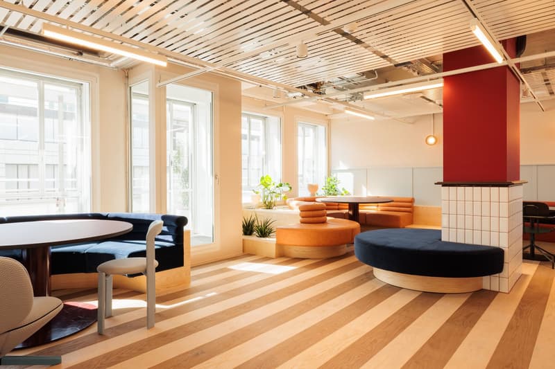 Spacious open-plan office with large windows, wooden ceiling beams, hardwood flooring, comfortable seating areas, and a fireplace feature