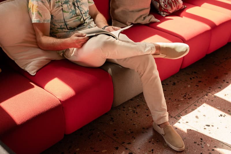 A person sitting on a red sofa, reading a book.
