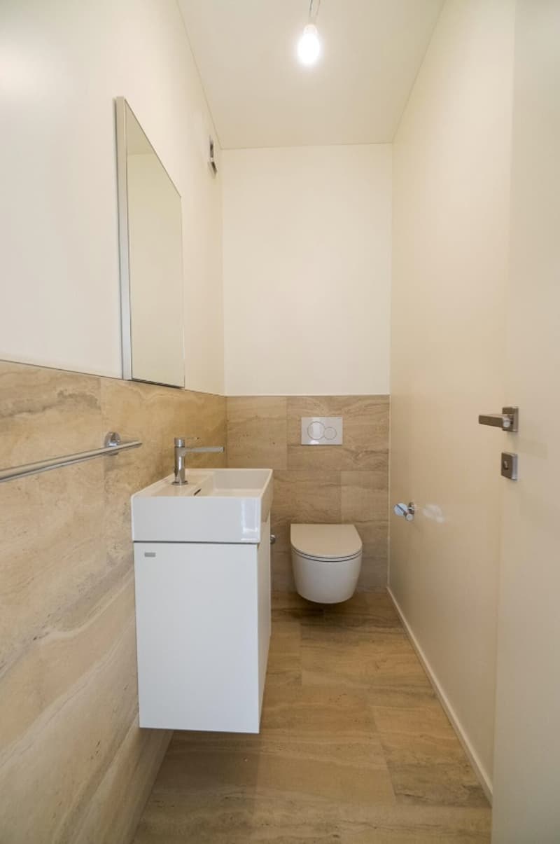 Bathroom with white vanity, toilet, and tiled walls and floor