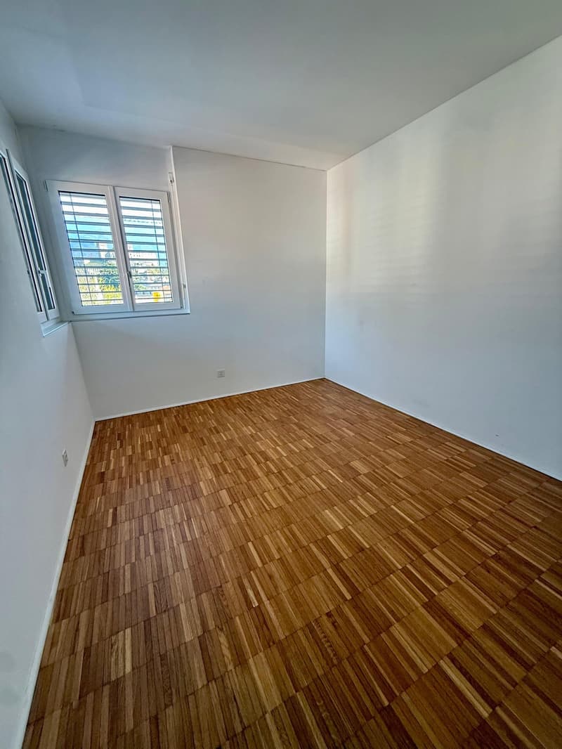empty room, wooden floor, white walls, two windows with blinds, power outlet