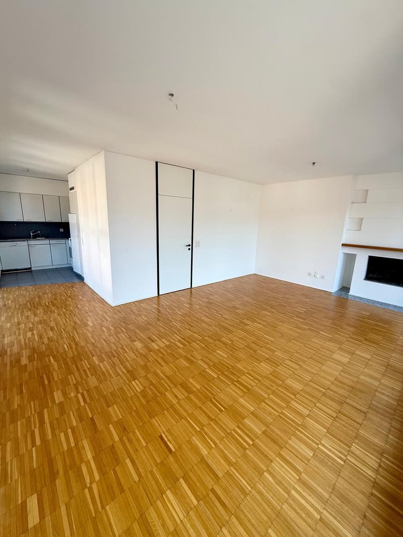 empty room, wooden floor, white walls, fireplace, kitchen area