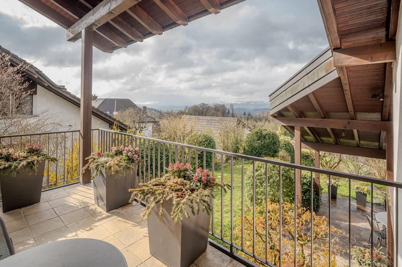 covered balcony, metal railing, tiled floor, large planters with plants, view of the mountains