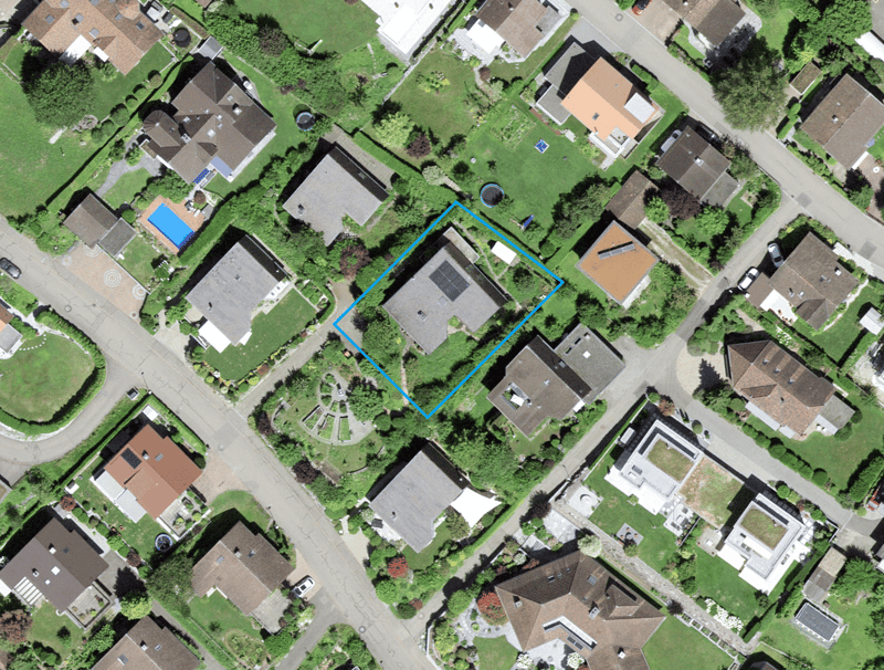 Aerial view of a neighborhood with several houses, one of which has a swimming pool and solar panels on the roof.