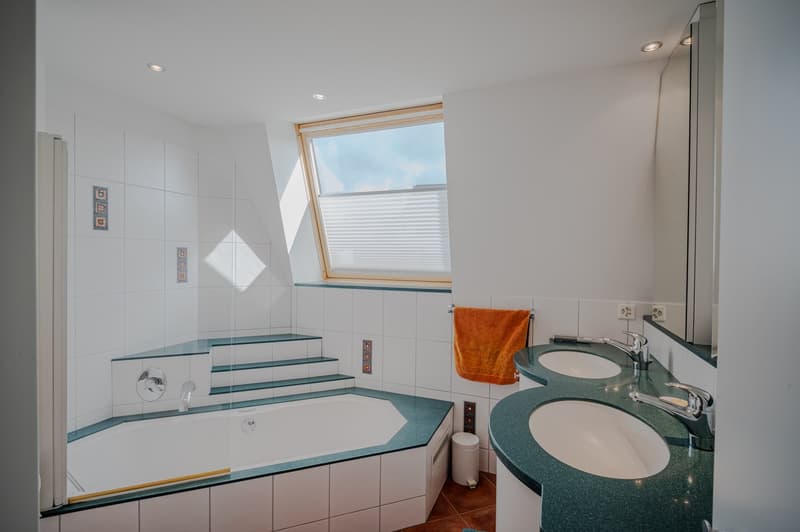 Bathroom with bathtub, double sink, mirror, and window
