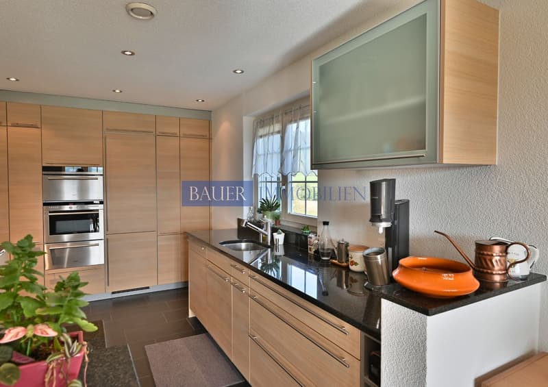 wooden cabinets, black granite countertop, stainless steel appliances, sink, faucet, copper watering can, microwave oven, double oven, wooden floors