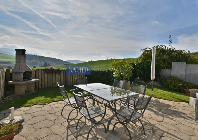 stone floor, seating area with table and chairs, outdoor oven, potted plants, fence, view of the hills