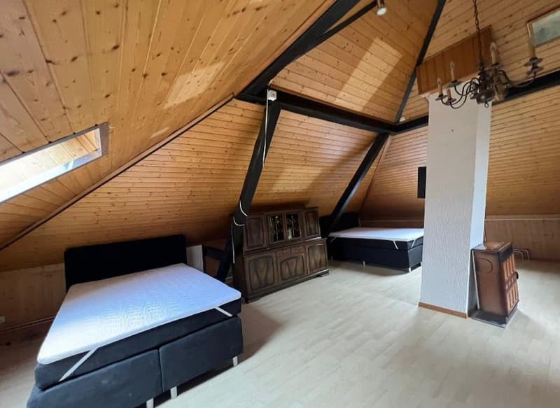 attic room with wooden walls, two beds, wooden cabinet, fireplace