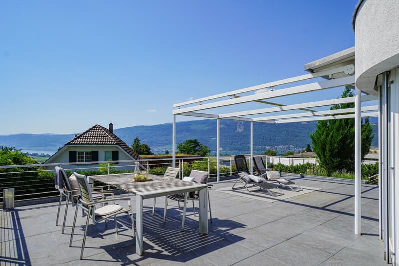 terraced garden with table and chairs, white metal frame pergola, view of the mountains