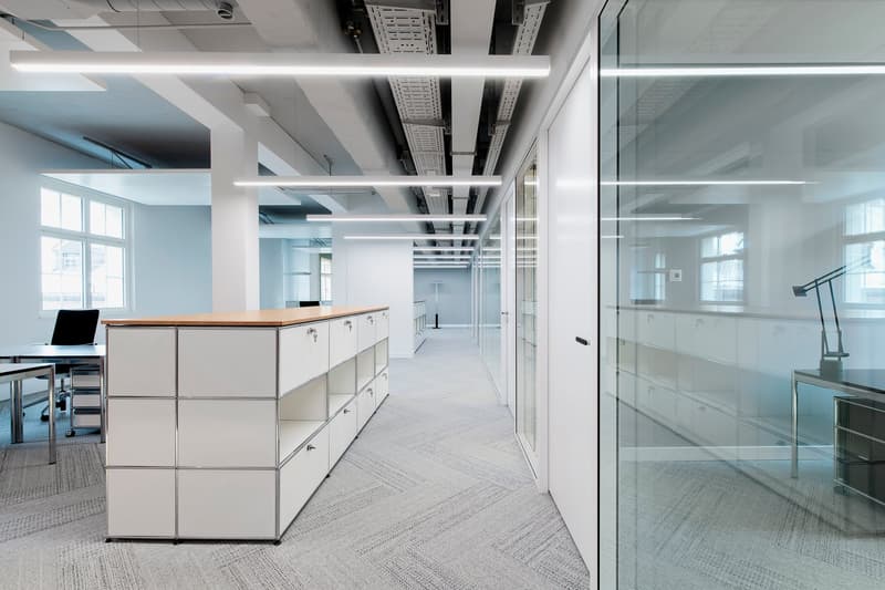 modern office space, white walls, glass doors, white cabinets, gray carpet, white ceiling lights