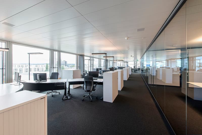 modern office with white cubicles, black carpets, glass windows and doors, office equipment