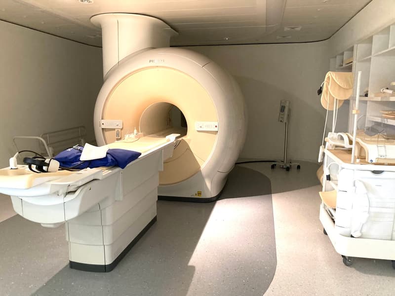 MRI machine, medical equipment, white walls, tiled floor, medical cart