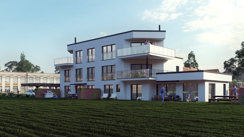 3-story modern apartment building with white exterior, large windows, and balconies. The building is surrounded by a grassy area with trees in the background.