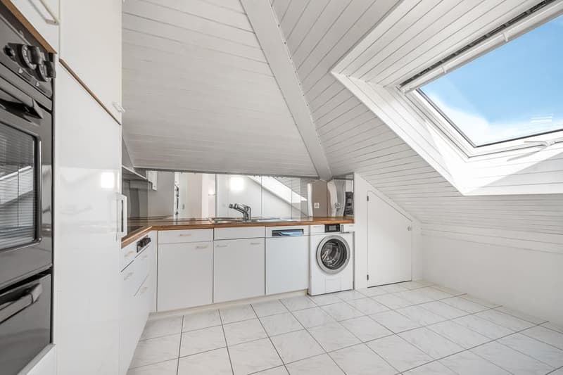 Attic kitchen with white cabinets, wooden countertops, built-in oven, and a washing machine