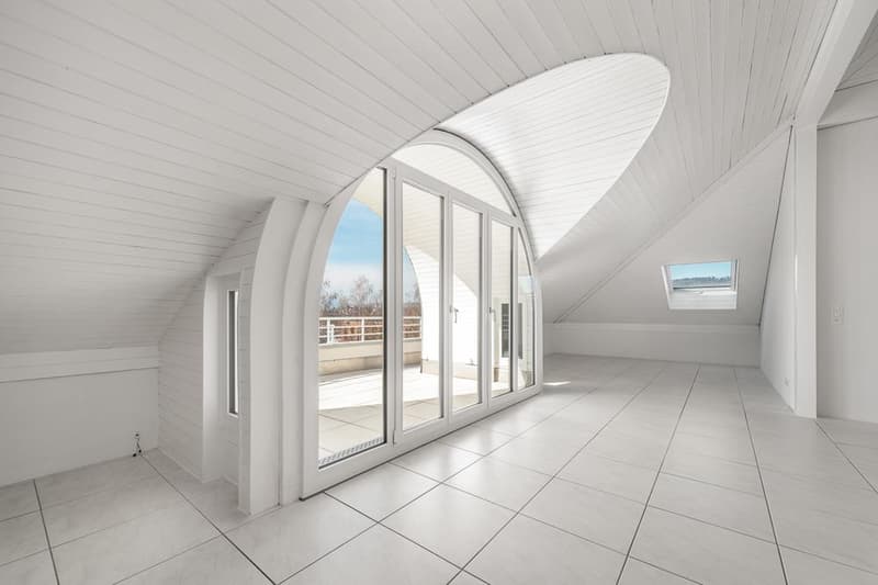 Spacious attic room with arched windows, white walls and ceiling, tiled floor, and access to a balcony or terrace