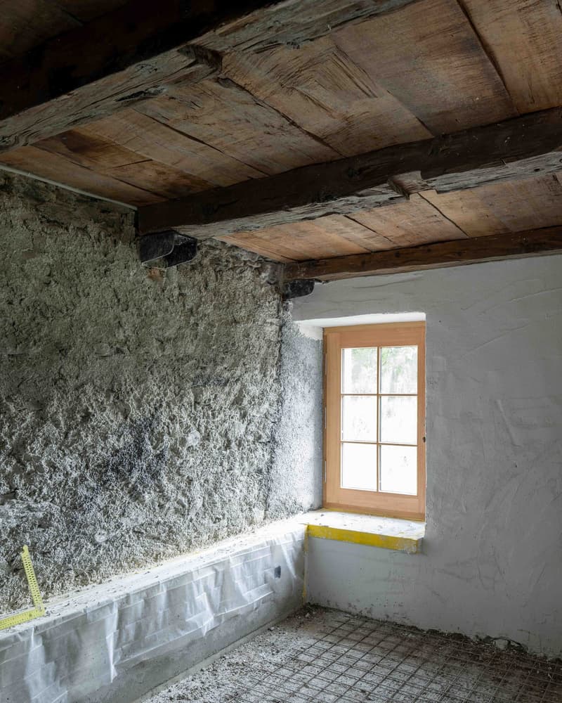 Stone wall, wooden ceiling, small window, cement flooring