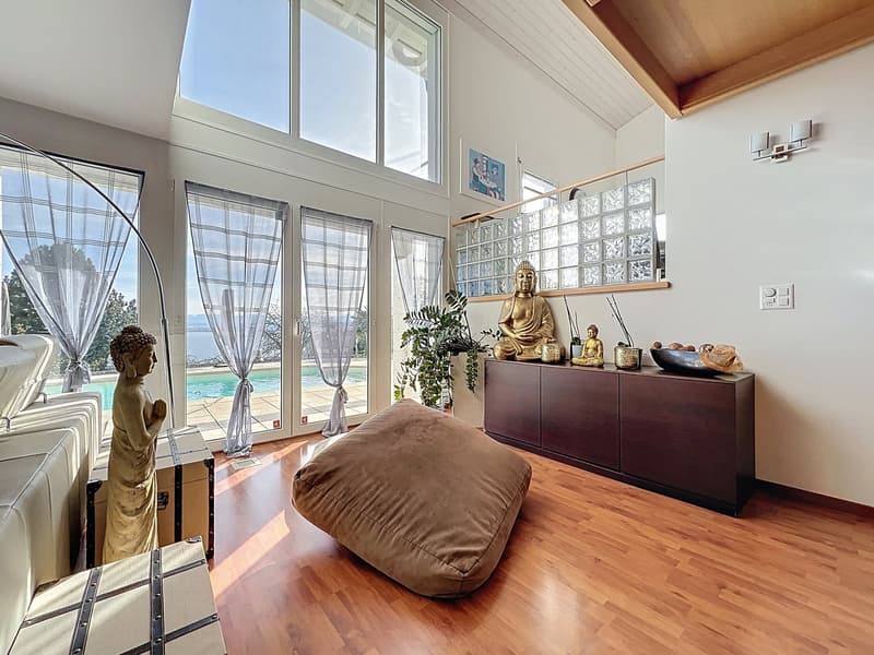 large windows, wooden floor, glass doors, Buddha statues, bean bag chair, wooden cabinet, plants, swimming pool view