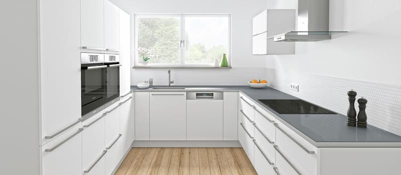 Spacious modern kitchen with white cabinets, black countertops, stainless steel appliances including a dishwasher, and large windows overlooking the outdoor scenery.