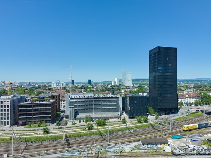 Aerial view of a city with multiple buildings, a railway track, and a clear blue sky.