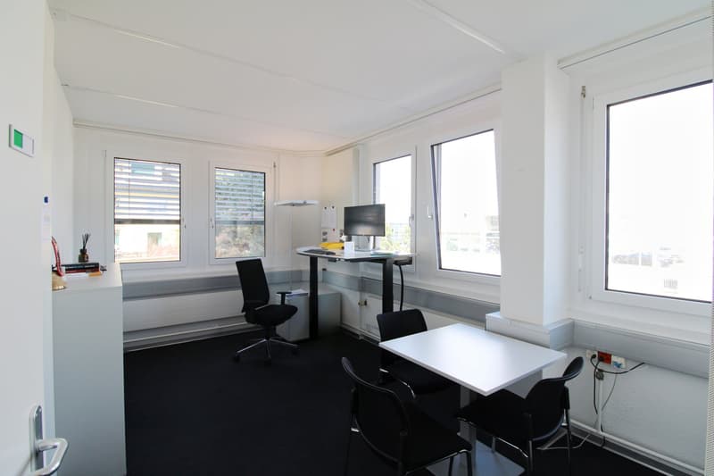 modern office room with desk, chairs, monitor, and windows