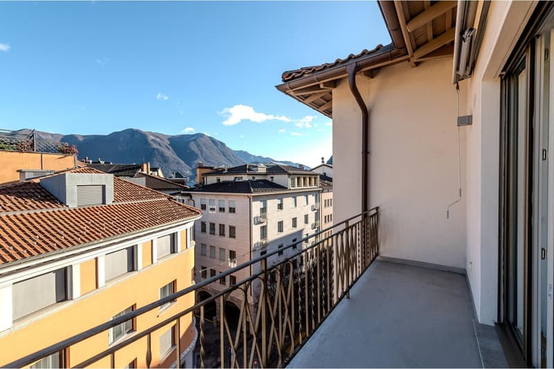Balcony with railings, tiled roof, mountains in the background