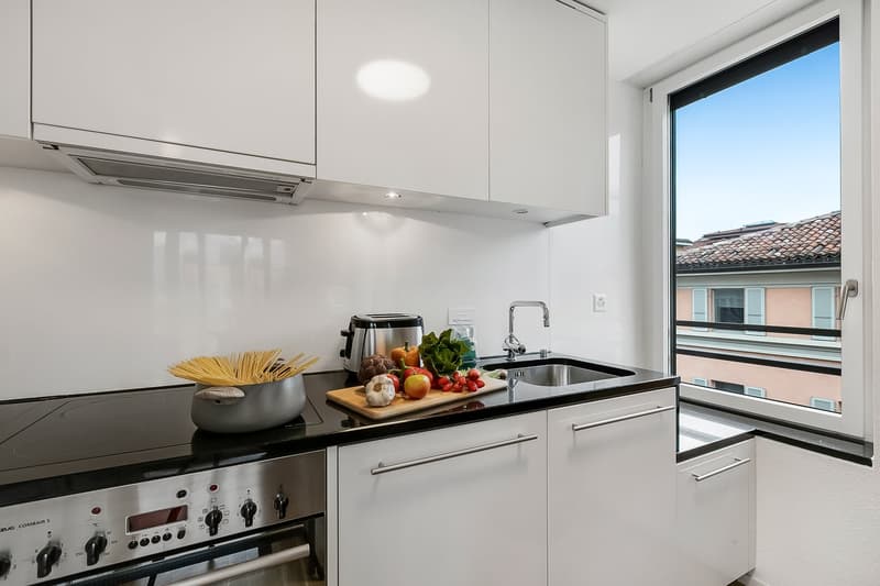 modern kitchen, white cabinets, black countertops, stainless steel appliances, large window with view