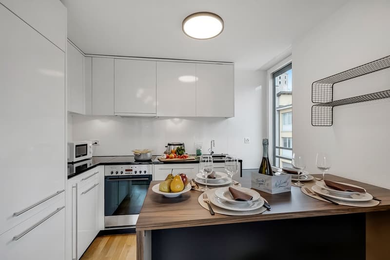 modern kitchen with white cabinets, wooden countertop, modern appliances, round ceiling light, dining area with table and chairs