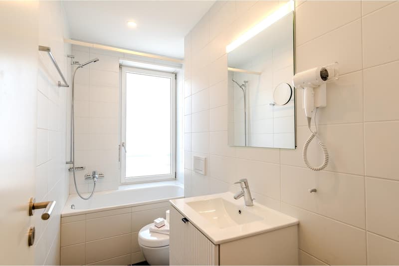 modern bathroom with bathtub, toilet, sink, mirror, and shower