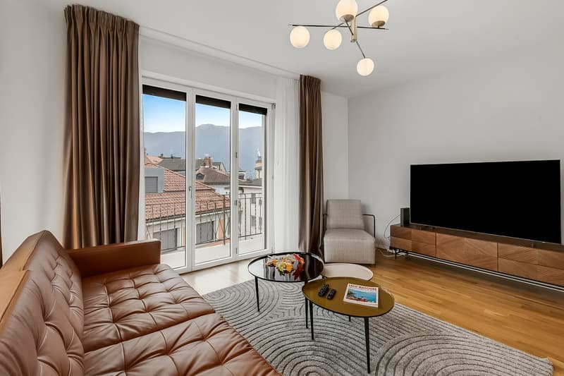 modern living room with leather couch, glass table, TV, balcony with view