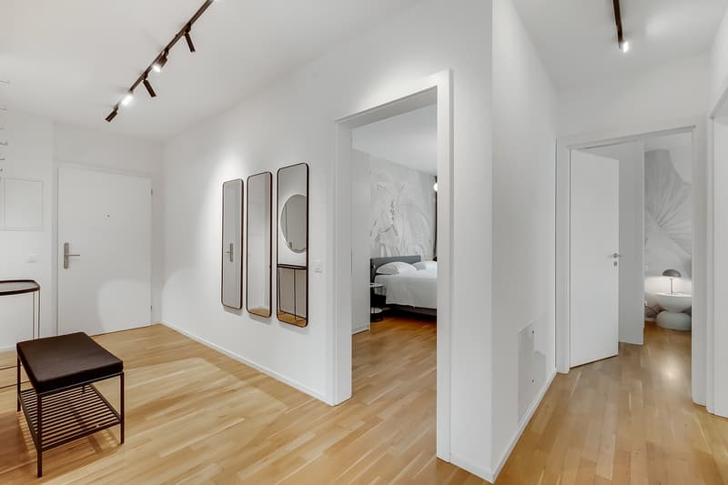 modern interior, white walls, wooden floor, three mirrors on wall, bed in bedroom, bedside table, lamp, stool