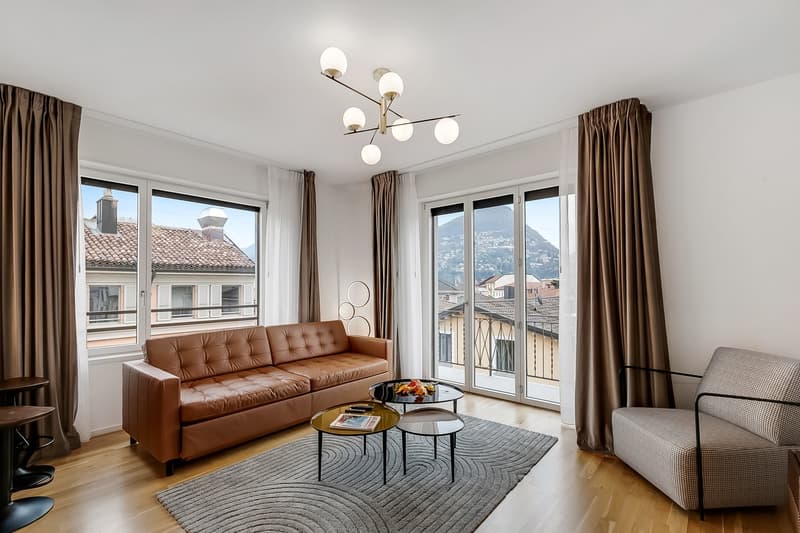 modern living room with brown leather sofa, coffee tables, carpet, large windows, balcony