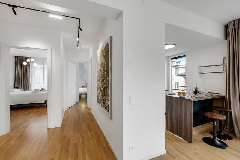 modern interior, wooden floor, white walls, open layout, kitchen island, dining area, bedroom visible