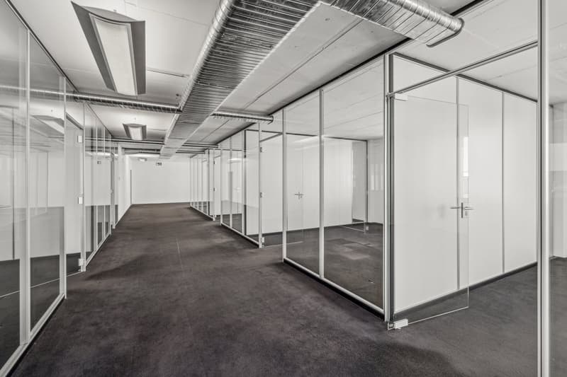 Glass walls and floor, carpeted flooring, silver pipes on ceiling, lights