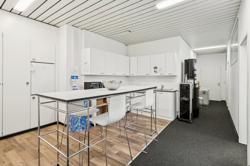 modern kitchen with white cabinets, wooden floor, stainless steel table, white chairs, refrigerator, microwave, sink, dishwasher, washing machine