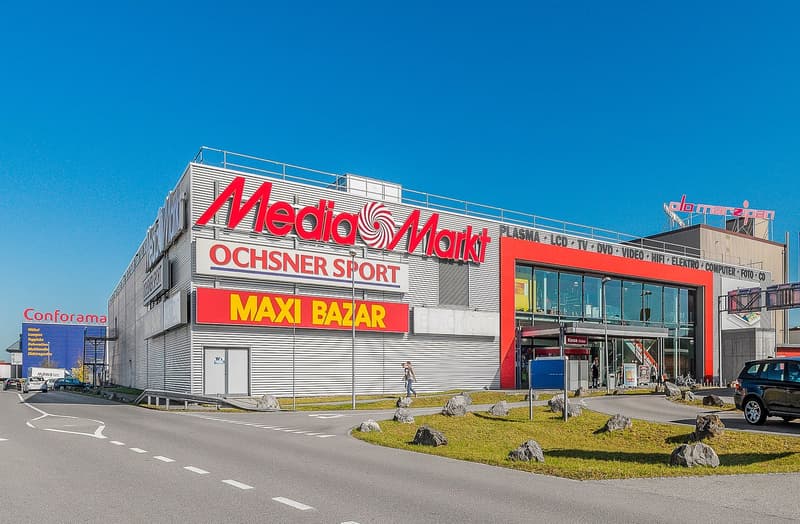 large commercial building with various shops and a parking lot