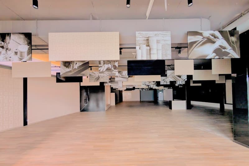 empty hall with wooden floor, square ceiling fixtures, hanging photo frames and spotlights