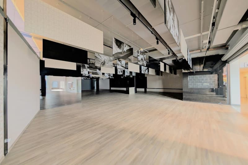 Empty room with large mirrors, hardwood floors, exposed ceiling beams, and framed artwork