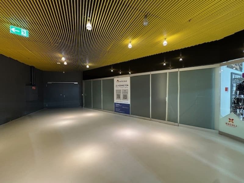 Empty room with white floor, yellow ceiling, glass walls, and a sign on the wall