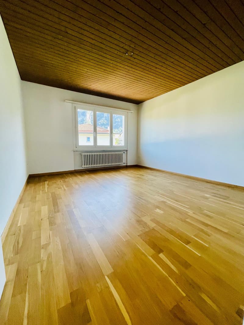 empty room, wooden floor, white walls, wooden ceiling, window with white curtains, radiator